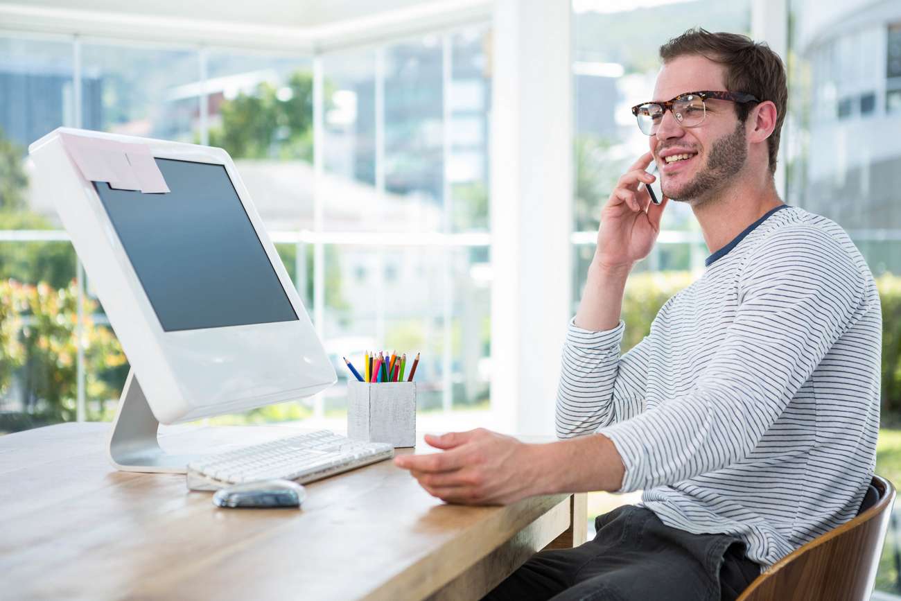 Handsome man working on computer and on the phone